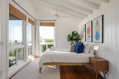 a white bedroom with a bed and a large window at Overlooking Luxury - Pool Heat - Spa - Games in Pico Rivera