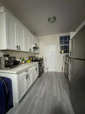 a kitchen with white cabinets and a wooden floor at Walk of Fame 1 Bedroom with shared bathroom and kitchen in Los Angeles