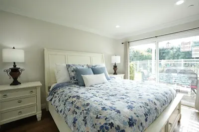 a bedroom with a bed with a blue comforter and a window at Sensational 6 Bedroom 4 Bathroom Pool Home (3 Master Bedrooms W/bathrooms) in Anaheim