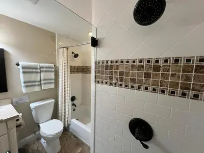 a bathroom with a toilet and a glass shower at Highly Upgraded, 5 Bed, 45 ba, New Pool w/Jacuzzi, 1/2 mile walk to Disney in Anaheim
