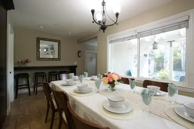 a dining room with a table with plates and flowers on it at Highly Upgraded, 5 Bed, 45 ba, New Pool w/Jacuzzi, 1/2 mile walk to Disney in Anaheim