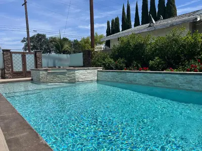 a swimming pool with blue water in a yard at Beautiful Remodel 3 Bedroom 2 bathroom Home with Pool & Jacuzzi in Fullerton
