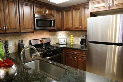 a kitchen with wooden cabinets and a stainless steel refrigerator at Luxurious 2 Bedroom Condo Shortest Walk To Disney in Anaheim