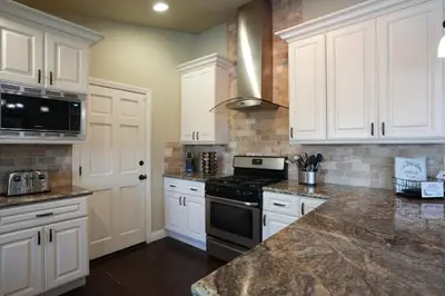 a kitchen with white cabinets and a stove top oven at Sweet 4 bedroom, 3 bath plus Loft Bedroom, Pool Home in Anaheim