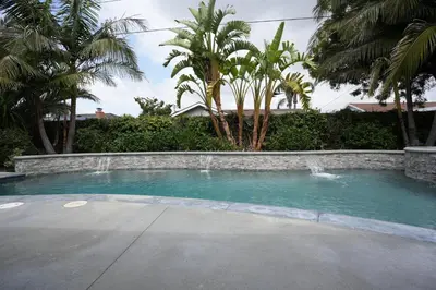 a swimming pool with a waterfall and palm trees at 4 bedroom, 3 bathrooms Pool Home in Orange