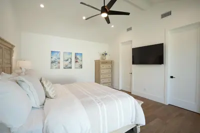 a white bedroom with a bed and a ceiling fan at 4 bedroom, 2 bathrooms in Orange