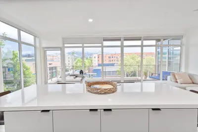 a kitchen with a white counter top and large windows at Glam by the Hollywood Sign 2 Bed Apt WITH FREE EV PARKING, Pool, Gym in Los Angeles
