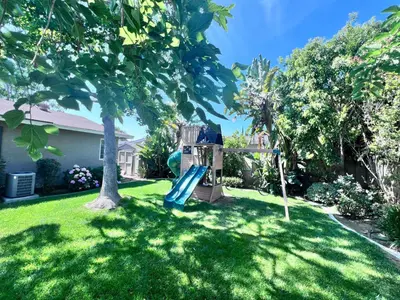 a playground in a yard with a tree at Charming Anaheim Home 1/2 Mile Walk to Disney in Anaheim