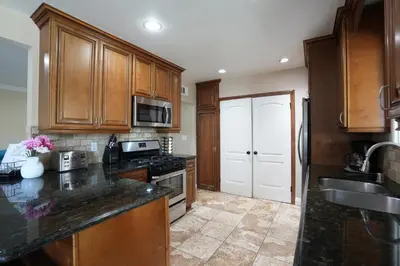 a kitchen with wooden cabinets and a black counter top at Charming Anaheim Home 1/2 Mile Walk to Disney in Anaheim