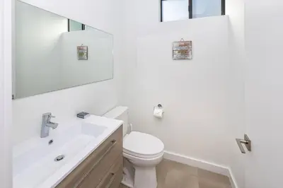 a white bathroom with a toilet and a sink at Modern 2BR Back House w/ TVs & Full Kitchen in Los Angeles
