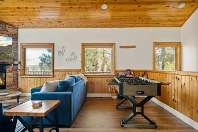 a living room with a blue couch and a table at Llama Bear Lodge with Hot Tub in Big Bear Lake