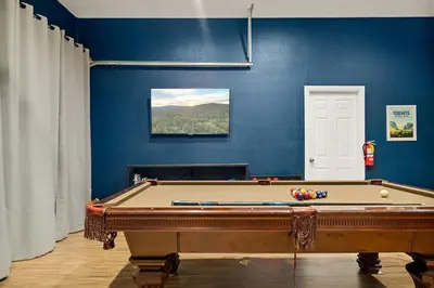 a room with a pool table and a blue wall at Llama Bear Lodge with Hot Tub in Big Bear Lake
