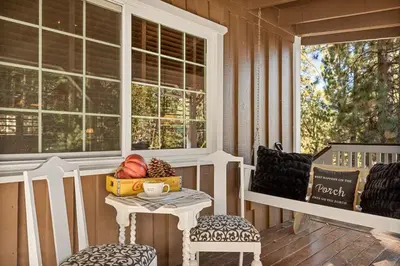 a porch with a table and two chairs and a window at Eureka Ranch Designer Cabin in Big Bear Lake