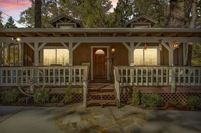 a house with a porch and a white fence at Eureka Ranch Designer Cabin in Big Bear Lake