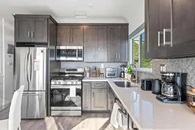a kitchen with wooden cabinets and stainless steel appliances at Luxury Beachside Gem Walk to Beach Ocean Views in Manhattan Beach