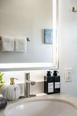 a bathroom sink with two bottles of soap and a mirror at Newly Remodeled Cozy Beach Retreat Ocean Views in Manhattan Beach