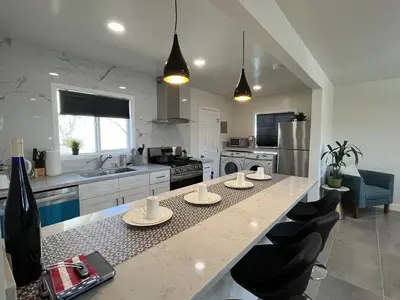 a kitchen with a counter with chairs and a counter top at Gated & remodeled 2b2b house 3373 in Baldwin Park