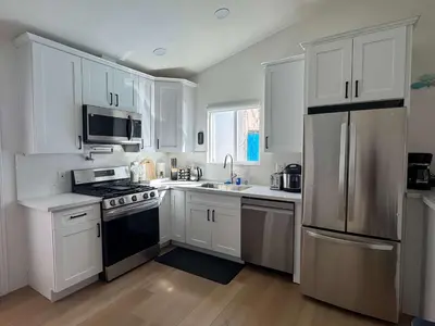 a kitchen with white cabinets and a black stove top oven at #Marbella Lane - Stylish Haven Near City Center in Long Beach