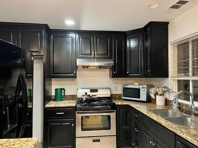 a kitchen with black cabinets and a stove top oven at Near Disney,college,sunset beach ,airport in Norwalk