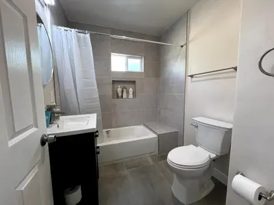 a bathroom with a toilet and a tub and a sink at Fully remoded 1B1B Home in baldwin Park3369A in Baldwin Park
