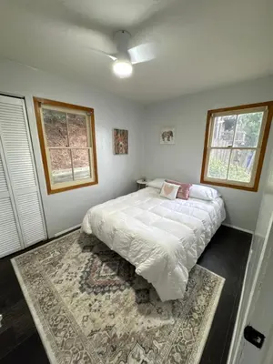 a bedroom with a large bed and two windows at Cozy Crestline Cabin Getaway in Crestline