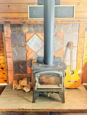 a fireplace with a stove and a guitar in a room at Cozy Crestline Cabin Getaway in Crestline