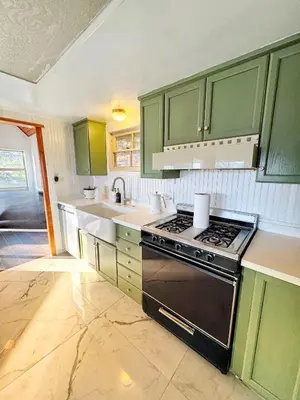 a kitchen with green cabinets and a stove top oven at Cozy Crestline Cabin Getaway in Crestline