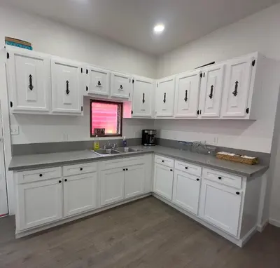 a kitchen with white cabinets and a sink at Naryn Guest house in Los Angeles