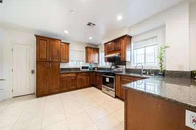 a large kitchen with wooden cabinets and a counter top at 40 ppl 2 houses 13 Bedrooms btw Disney Hollywd in Monterey Park