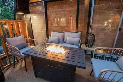 a fire pit on a patio with chairs and a table at Sequoia A-frame Nirvana: Modern + Views + Hot Tub in Ponderosa
