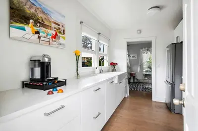 a kitchen with white cabinets and a refrigerator at Bougainvillea Bungalow Peaceful Venice Retreat in Los Angeles