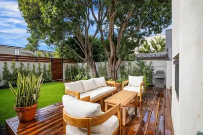 a patio with white chairs and a wooden table at Pacific Breeze - Modern Venice Beach Home in Los Angeles