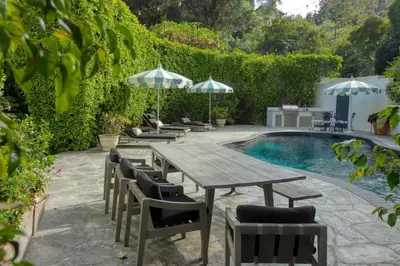 a patio with a wooden table and chairs next to a pool at Laurel Canyon Classic Hollywood Residence With Pool in Los Angeles