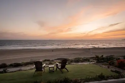 two chairs and a table on the beach at sunset at New Listing The Nautilus Manhattan Beachfront Retreat in Manhattan Beach