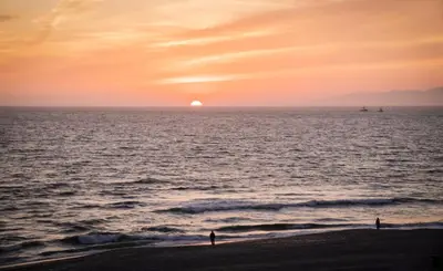 two people standing on the beach watching the sunset at New Listing The Nautilus Manhattan Beachfront Retreat in Manhattan Beach