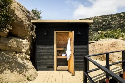 a black outhouse with a wooden door and a rock at Retreat to the Rocks Historic Film And Music Getaway in Chatsworth Lake Manor