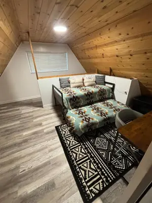 a living room with a bed and a rug at The Honey Bear Cabin Jacuzzi EV Friendly Renovated in Green Valley Lake