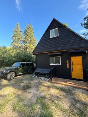 a truck parked in front of a black house at The Honey Bear Cabin Jacuzzi EV Friendly Renovated in Green Valley Lake