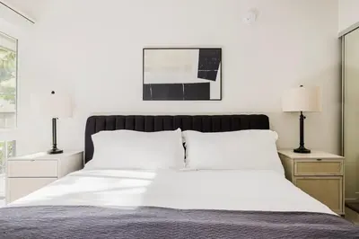 a bedroom with a bed with white sheets and two lamps at Blueground Burbank pool bbq nr studios LAX-1321 in Los Angeles