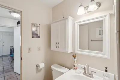 a white bathroom with a sink and a mirror at Beach Condo with Private Patio #133 in Carpinteria