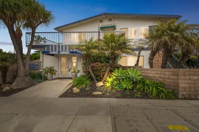 a house with palm trees in front of it at 1 Bed Beach Condo #131 in Carpinteria