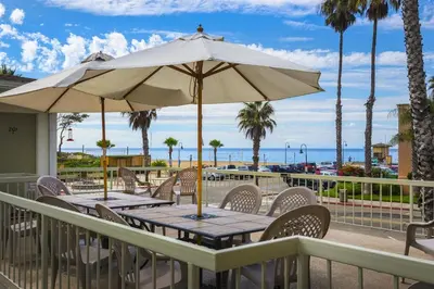 a table with an umbrella on a deck with the beach at Full 1 Bed Beach Condo #227 in Carpinteria