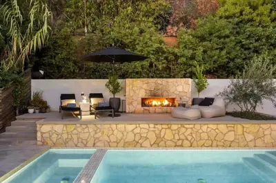 a swimming pool with a fireplace next to a patio with a fire place at Hollywood Hills Villa by Universal - Pool - Dogs OK in Los Angeles