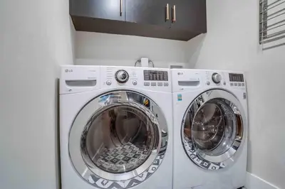 two washing machines in a white laundry room at Projector - Pool Table - 15min DT - Pets OK - BBQ in Los Angeles