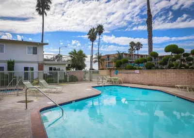 a swimming pool with chairs and a building and palm trees at 4980 Sandyland Road #215 in Carpinteria