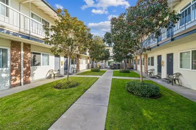a walkway between two buildings with trees and grass at 4980 Sandyland Road #215 in Carpinteria
