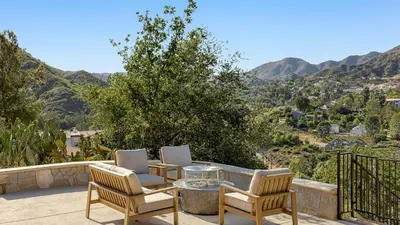 a patio with two chairs and a table on a balcony at Designer Retreat w Pool Firepits Panoramic Views The Lake House at Malibu in Agoura Hills