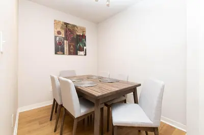 a dining room table with white chairs and a painting at Cozy 2BR Apt in Downtown LA with Pool & Hot Tub in Los Angeles