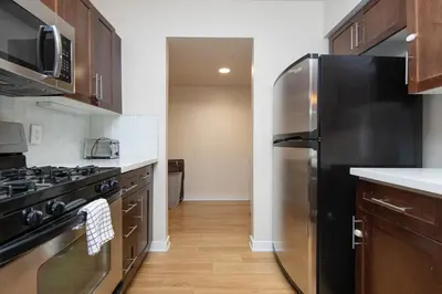 a kitchen with a stainless steel refrigerator and wooden cabinets at Cozy 2BR Apt in Downtown LA with Pool & Hot Tub in Los Angeles