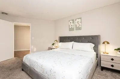a white bedroom with a large bed with white sheets at 2BR Hollywood Apt with Rooftop Pool & Stunning Views in Los Angeles